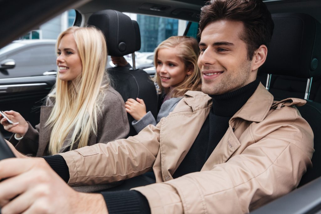 Smiling young family sitting in car